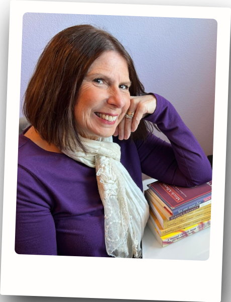 Therese leaning against a stack of books and smiling.