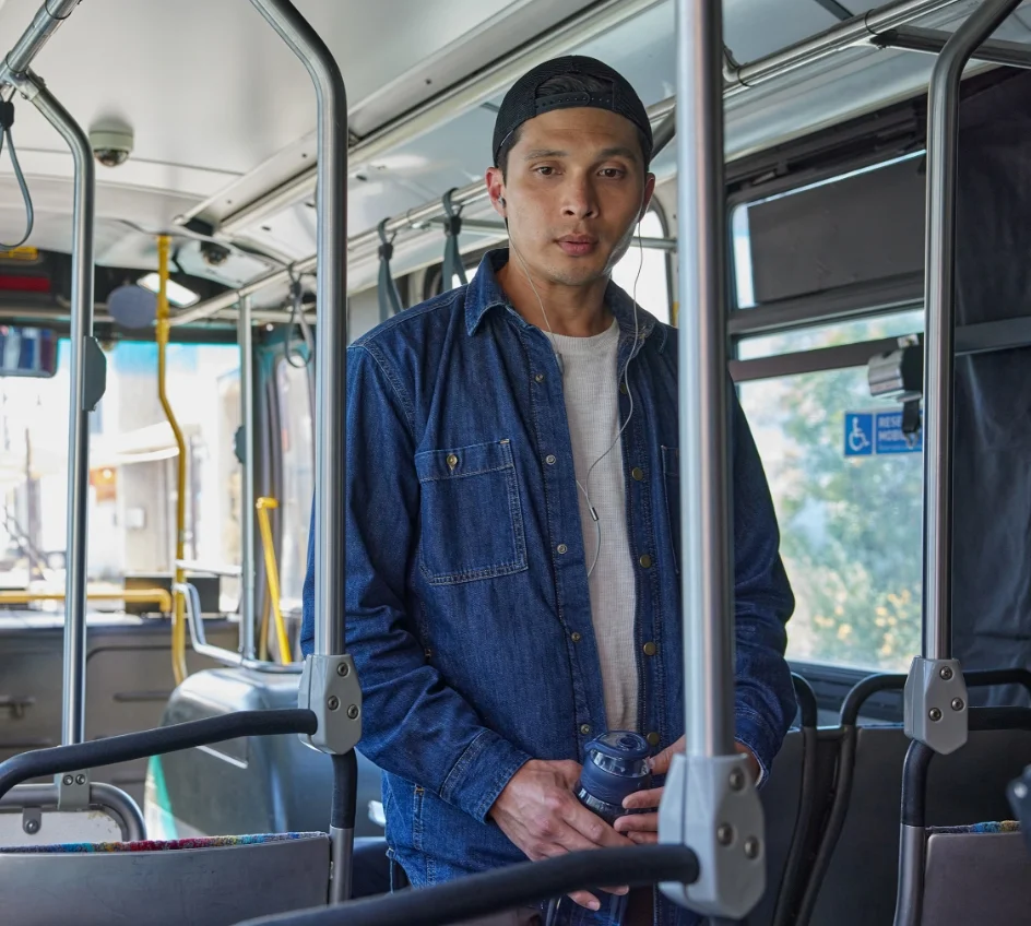 Man holding a water bottle standing in a bus