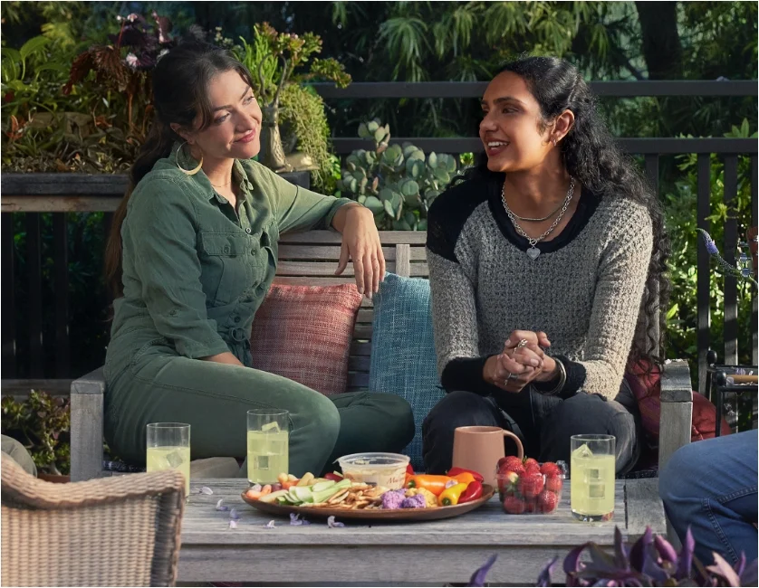 Two women sitting at a table outside and talking