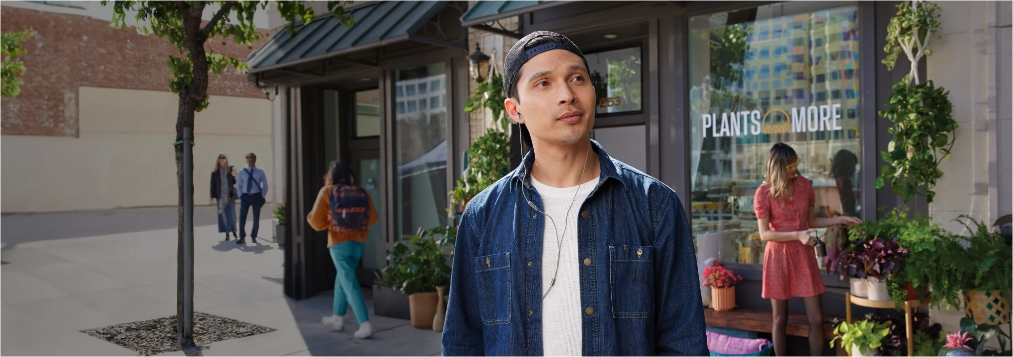 Man walking down the sidewalk in front of a plant store, listening to music